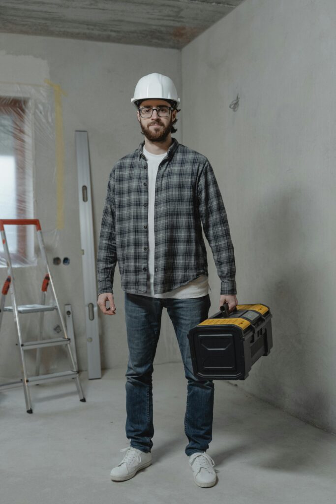 Construction worker in plaid shirt with toolbox indoors, showcasing renovation setting.